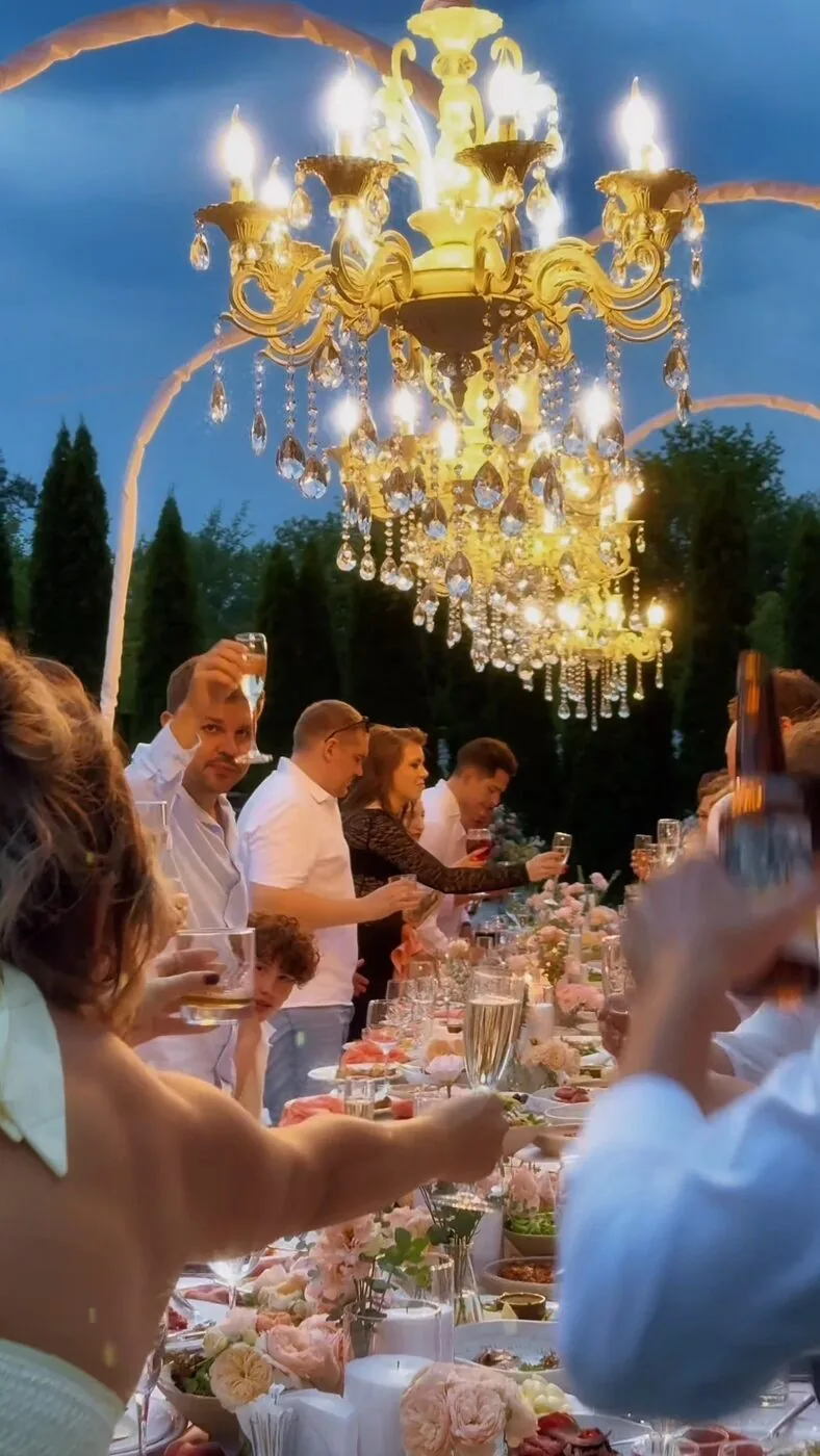 Wedding reception under a chandelier, guests raising their glasses